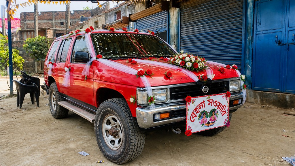 Red Nissan Pathfinder decorated for a wedding with flowers and Behula Sawari signage